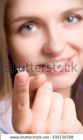 A girl holds a contact lens, focus on the lens