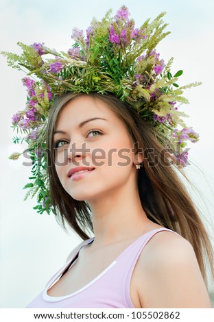 Beautiful brunette girl in a wreath of wild flowers