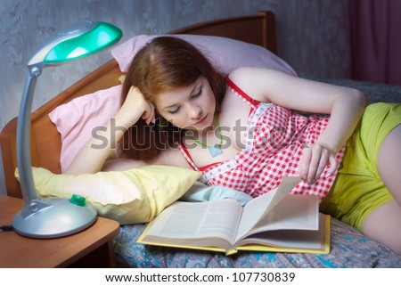 A girl reads a book in bed at night