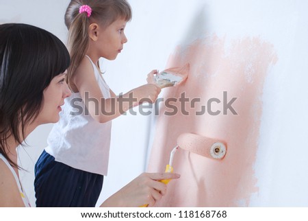Young woman and child painting the walls, repair