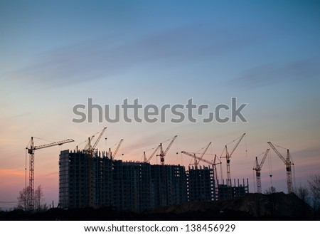 Industrial construction cranes silhouettes on sunset