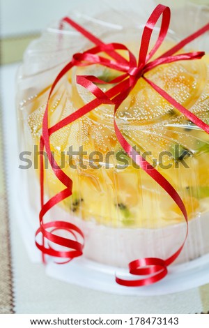 Cake with pieces of fruit in jelly is packaged with a bow
