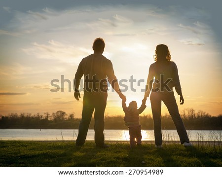 family at sunset standing on the bank of the river