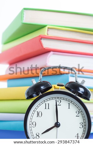 Alarm clock and stack of books on a white background