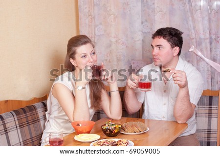 Spouses talk on kitchen behind a table