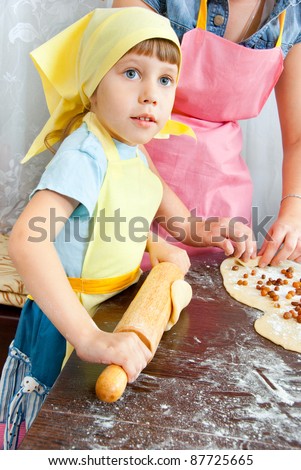 The girl rolls the dough with a rolling pin