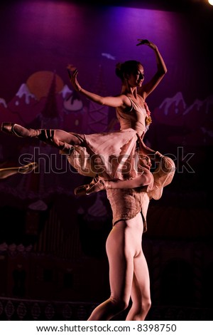 classic ballet male dancer rising female dancer bright lit by stage lights on dark background