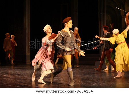 couples of classic ballet female and male dancers dancing with foils lit by stage lights