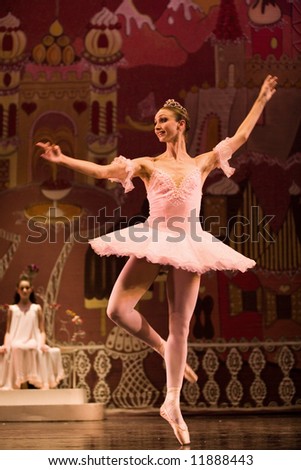 classic ballet female dancer solo in pink dress on stage lit by stage lights
