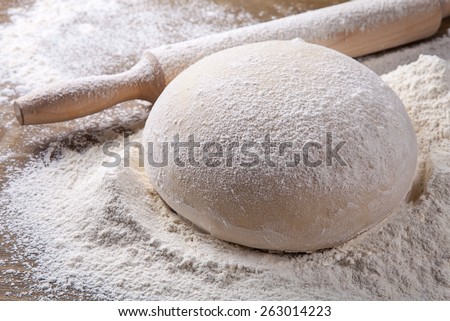 wooden rolling pin with dough and dusting of flour.