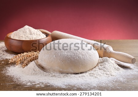 wooden rolling pin with dough and dusting of flour.