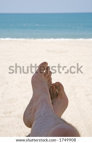 view of relaxed feet with beach and ocean in the background