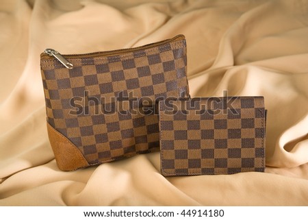 Cosmetic bag and Wallet on fabric background