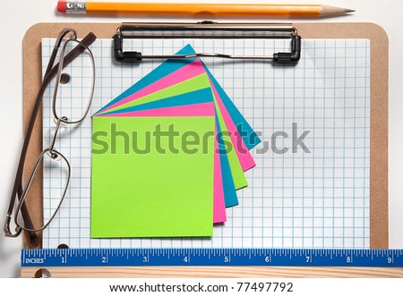 Clip board with grid paper, notes, pencil, ruler, and glasses with white background