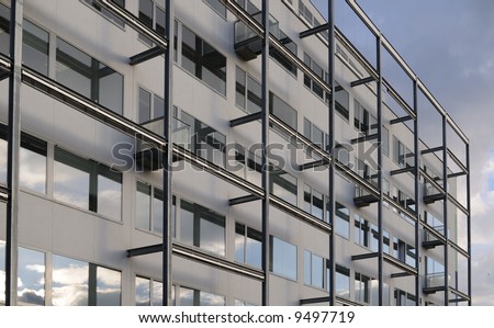 Modern office building with window and balcony, against blue sky.