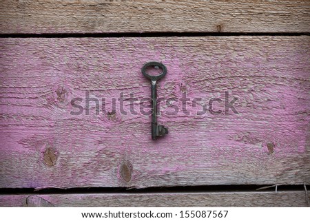 Old antique key hanging on wooden rustic pink background