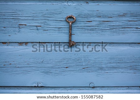 Old antique key hanging on wooden rustic blue background