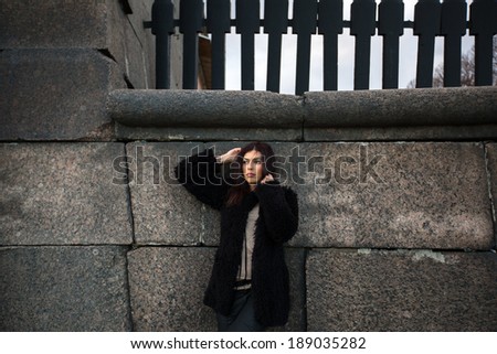 Beautiful woman standing alone near the old granite wall