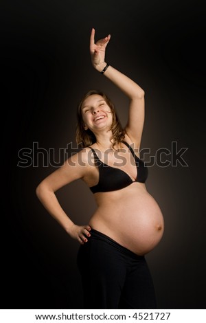 stock photo Happy pregnant woman dancing against black background