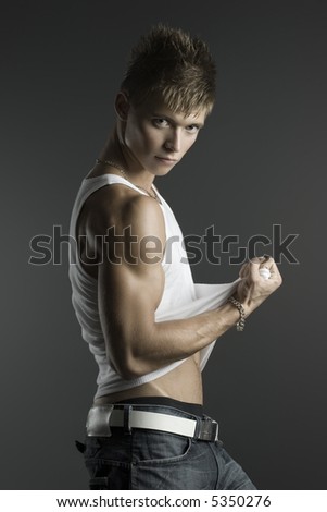 Handsome fashionable guy in white t-shirt and jeans posing in studio