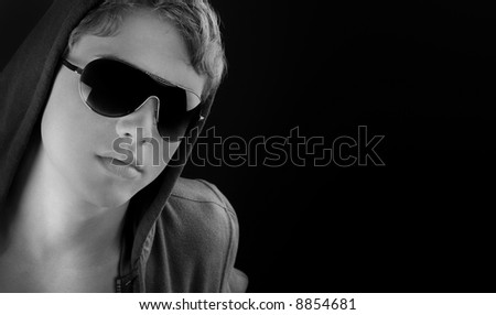 Young fashion man model posing in sun glasses. Black and white version.