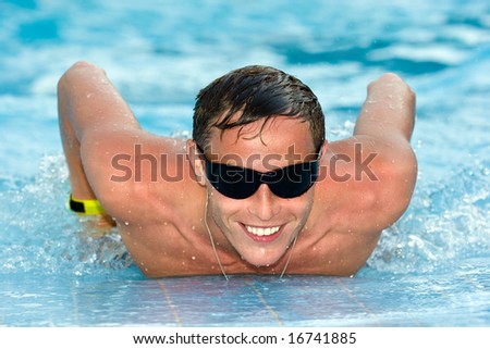 Young and positive man with athletic body relaxing in swimming pool