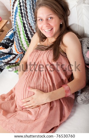Happy pregnant woman laying on the sofa.