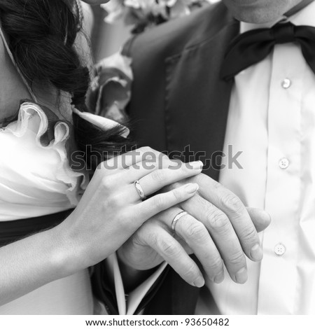 Hand of the groom and the bride with wedding rings. Monochrome image.