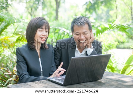 Woman sitting use computer on wooden table at home office ,background of green trees.
