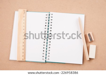 open diary or photo album book on brown background has pencils, erasers, rulers
