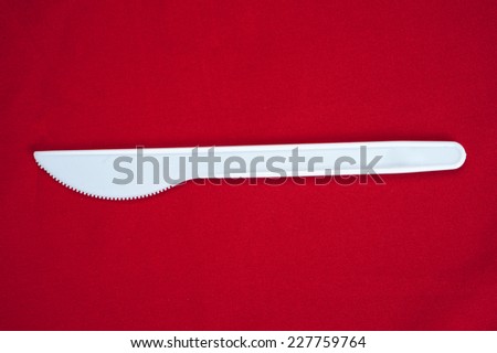 White plastic knife , knife on red background.