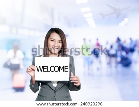 Asian businesswoman with long hair holding a sign board with a welcome has airport background.Mixed Asian / Caucasian businesswoman.