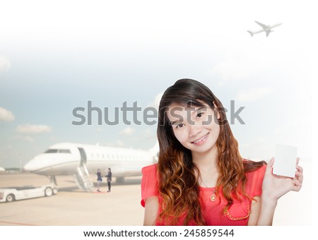 portrait of asian  businesswomen wearing red and hold card has airport background .Mixed Asian / Caucasian businesswoman.Positive emotion