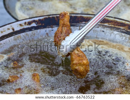 Breaded chicken deep frying in oil in a cast iron frying pan