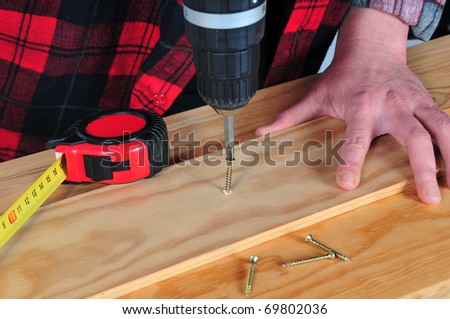 hands with tool of screwing on wooden list