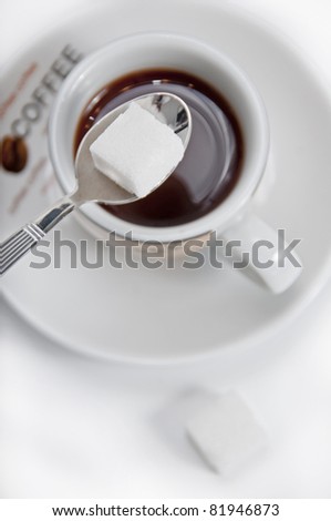 cup of coffee with first teaspoon plane and clod of sugar
