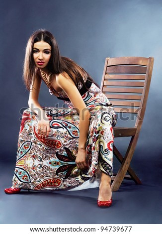 Fashionable woman in long dress sitting on a chair