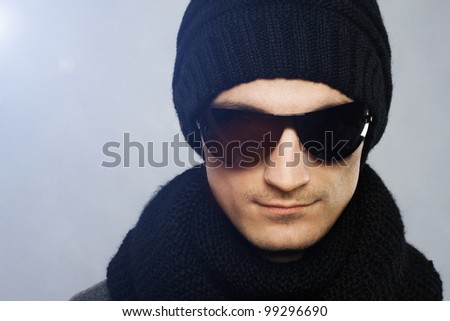 Studio portrait of stylish handsome man in dark sunglasses and black clothing