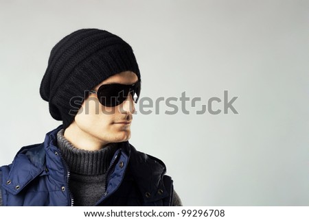Studio portrait of stylish handsome man in dark sunglasses and down-padded coat