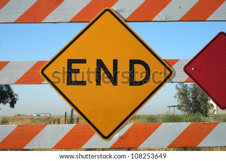 Sign and barrier mark the end of a road and suggest a visual concept of an ending