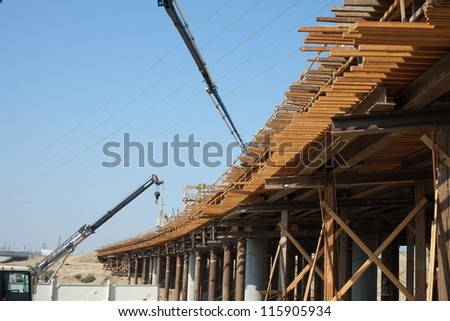 BAKERSFIELD, CA-OCT 16: Concrete pouring has begun on new bridge across the Kern River by pumping in flexible hoses supported by articulated cranes on October 16, 2012, in Bakersfield, California.