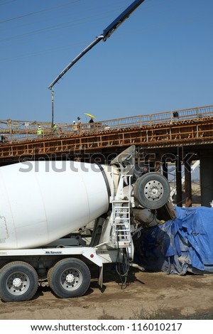 BAKERSFIELD, CA-OCT 16: Concrete pouring has begun on new bridge across the Kern River by pumping in flexible hoses fed by transit mix trucks on October 16, 2012, in Bakersfield, California.