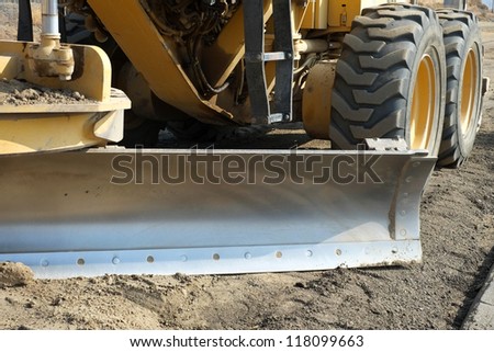 Steel scraper blade is mounted on construction equipment engaged in building new road