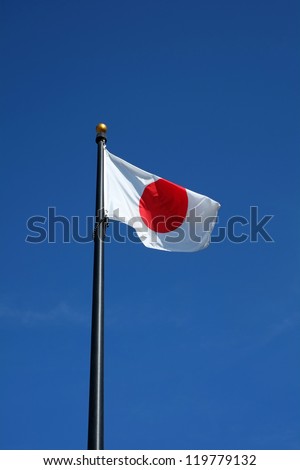 The Japanese flag flies in the wind against a clear blue sky