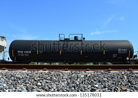 An oil tank car sits on a railroad siding awaiting delivery to destination