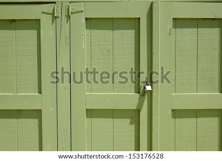 Background or texture: A green-painted wood storage locker is secured with a padlock