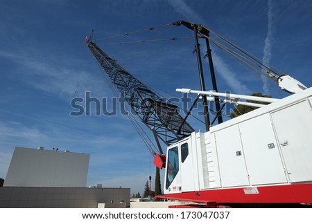 A crane with a one hundred foot mast has a long reach over this construction job site.