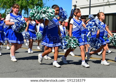SHAFTER, CA - MAY 3, 2014: These little girls, members of the Redwood School\'s pep squad, are having a good time marching in the Cinco de Mayo Celebration parade.