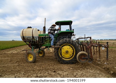KERN COUNTY, CA-MAY 20, 2014: Central California farm worker, Jesus Urrell, mounts a tractor, ready to apply chemical fertilizer to a field of commercially-grown roses.