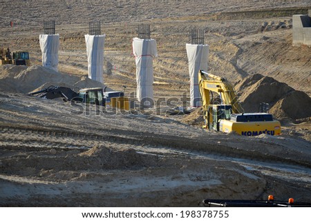 BAKERSFIELD, CA-JUNE 12, 2014: Heavy earth moving machinery works on the project to widen State Route 178. Concrete columns and bridge abutment are taking shape.